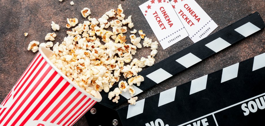 Popcorn, cinema tickets and movie clapper on grunge background